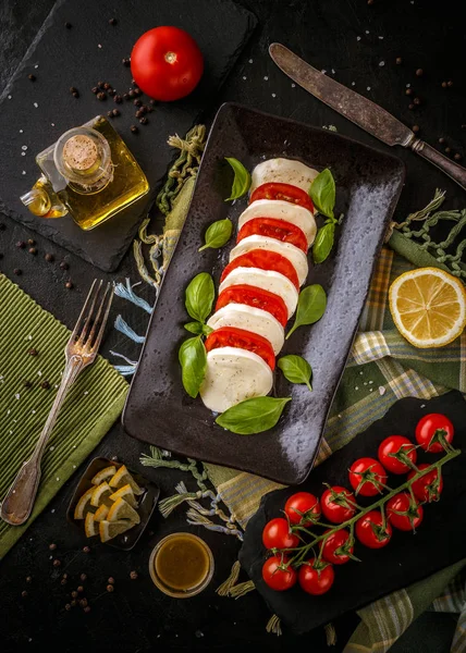 新鮮なイタリアのカプレーゼサラダとモッツァレラチーズとトマトのダークプレート — ストック写真
