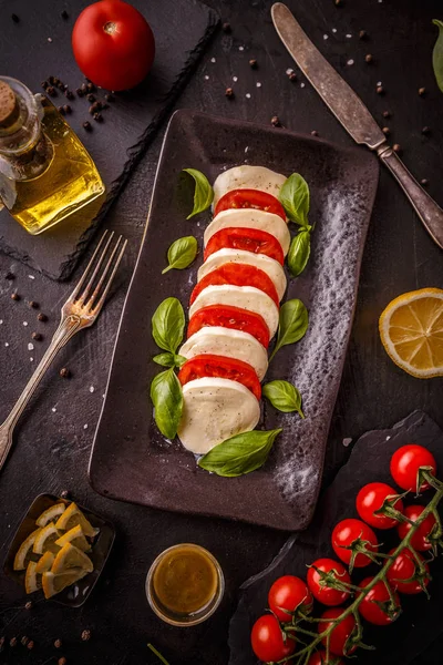 新鮮なイタリアのカプレーゼサラダとモッツァレラチーズとトマトのダークプレート — ストック写真