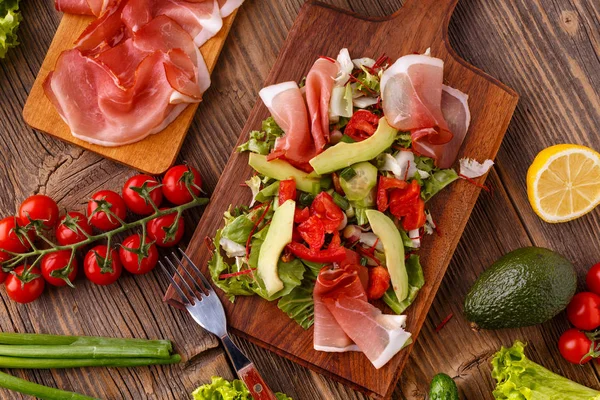 Tedavi jambon ve ahşap kesme tahtası üzerinde taze sebze salatası