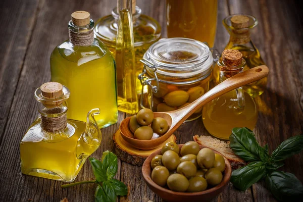 各种橄榄油玻璃瓶与橄榄浆果在质朴的木质背景 — 图库照片