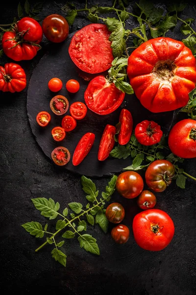 黑色背景下的全红色西红柿和西红柿片 — 图库照片