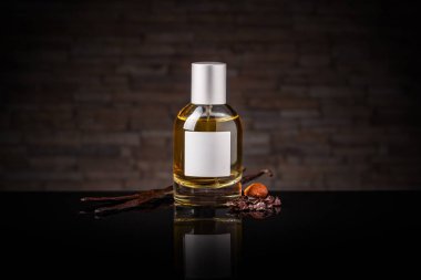 Parfüm şişesi ve koyu arkaplanda vanilya kapsülleri