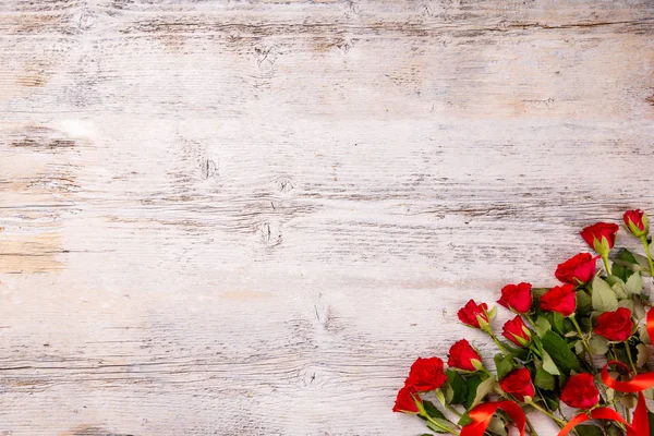 Rosas vermelhas na mesa de madeira branca — Fotografia de Stock