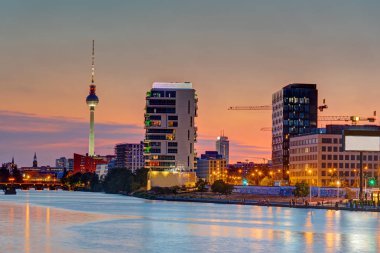 Arkadaki ünlü televizyon kulesi ile Berlin'de Spree Nehri, alacakaranlıkta