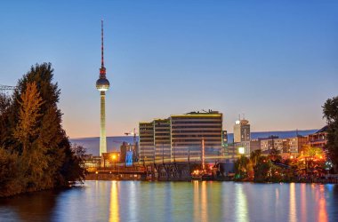 Arkadaki ünlü televizyon kulesi ile Berlin'de Spree Nehri, alacakaranlıkta