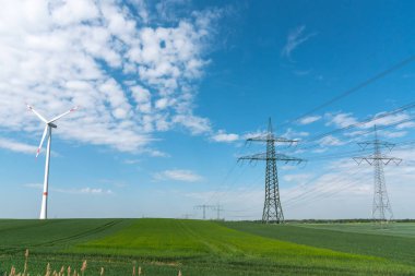 Almanya kırsalında elektrik hatları ve rüzgar türbini görülüyor
