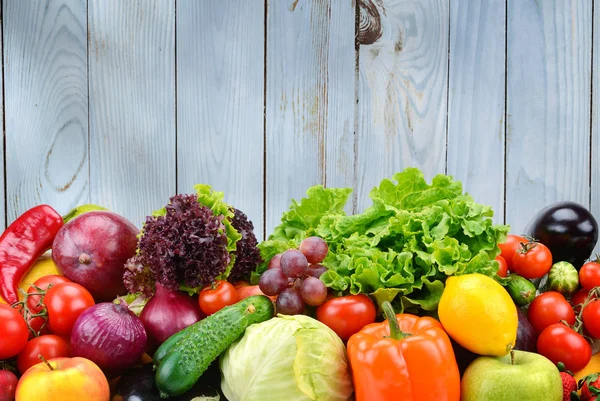 Nützliches Gemüse und Obst auf hellblauem Holzwandhintergrund — Stockfoto