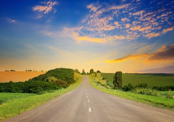 絵のような風景の上に日の出 直線道路や畑の照明光線日 — ストック写真
