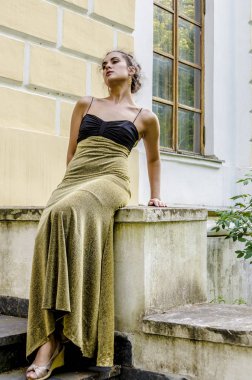 Eski bir evin balkonunda uzun kokteyl elbiseli güzel esmer kız