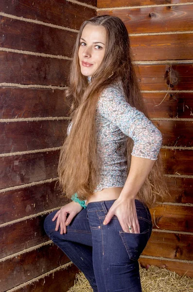ヘアロフト付きの素朴な納屋に長い茶色の髪とジーンズを持つ女の子 — ストック写真