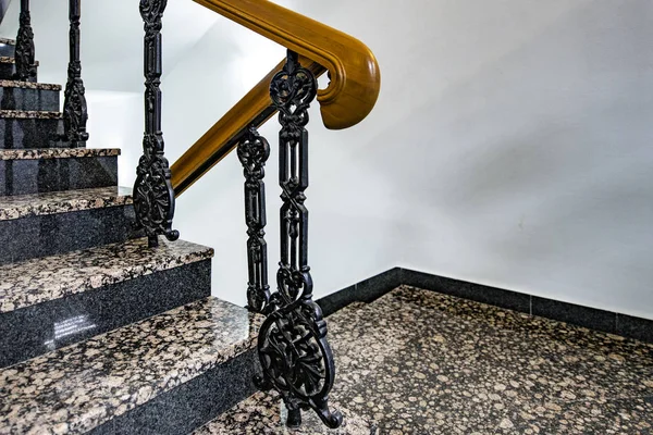 Staircase with forged railings on the railing in the old stairwell