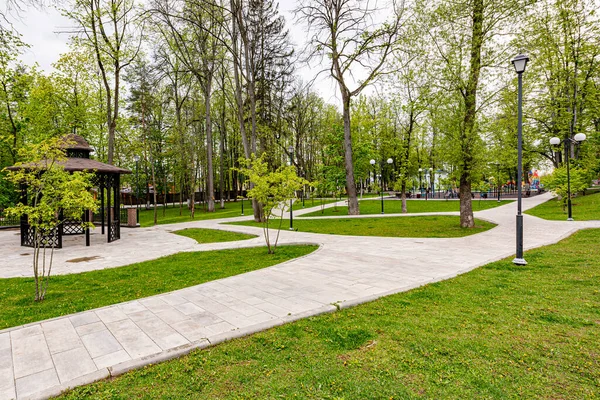 Frühlingspark Mit Steinernen Gehwegen Und Bänken lizenzfreie Stockbilder