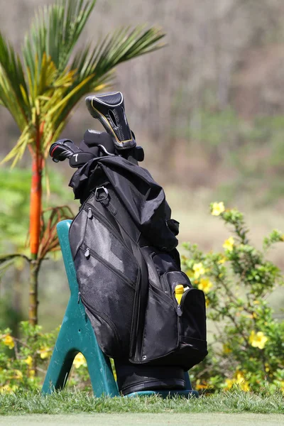 Black golf bag with clubs on a practice green at a golf course