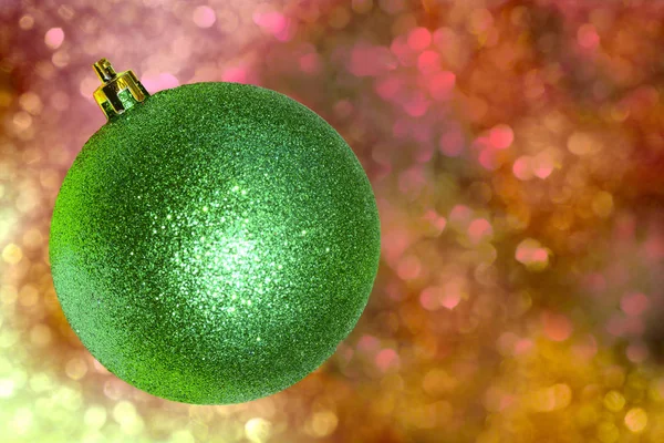 Grüne Weihnachtskugel Über Rotem Glänzenden Hintergrund Für Eine Weihnachtskarte — Stockfoto