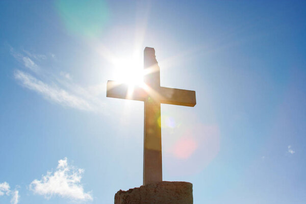 Big christian cross with sun light rays and blue sky