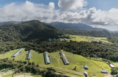 Güzel dağlarla çevrili bir vadideki birkaç kümes hayvanının hava manzarası.