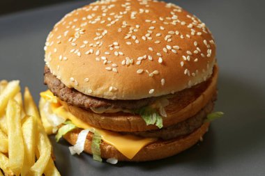 Lezzetli taze burger marul, peynir ve soğan ve kişiler karanlık bir arka plan üzerine Close-up