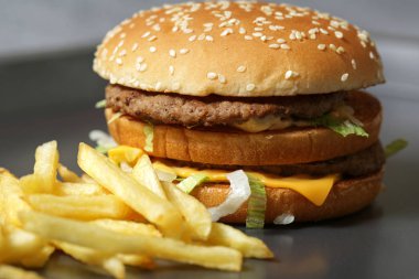 Lezzetli taze burger marul, peynir ve soğan ve kişiler karanlık bir arka plan üzerine Close-up