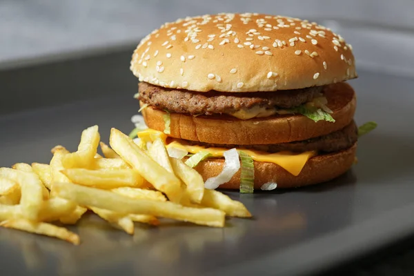 Lezzetli taze burger marul, peynir ve soğan ve kişiler karanlık bir arka plan üzerine Close-up