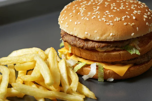 Lezzetli taze burger marul, peynir ve soğan ve kişiler karanlık bir arka plan üzerine Close-up