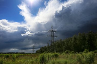 Tarla, çayırlar ve ormanlar ve gökyüzündeki güzel gök gürültülü bulutlar ile elektrik telleri ve direkleri güneş ışığını engellemek