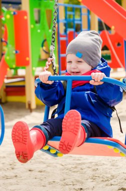 iki yılda bir mavi ceket ve kırmızı eşarp iyi sevimli adamsın parlak çocuk oyun oynuyor, bir çocuğun salıncak üzerinde bir gezintiye gider
