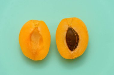 Kayısı Yeşil bir arka plan üzerinde iki yarısı. Yarı yarıya kayısı kesti. Minimalizm