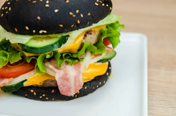 Black burger with meat, barbecue and cheese on a table in a restaurant. Cool fast food beautiful burger restaurant