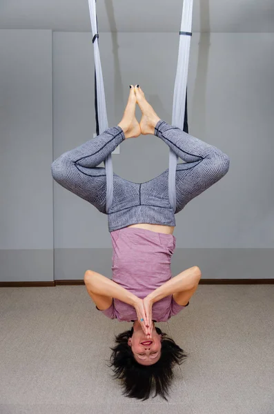 Woman hanging upside down in a hammock. Fly yoga class. Healthy lifestyle, healthy hobby. In a healthy body healthy mind