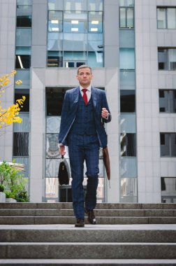 Merdivenlerden aşağı gelen bir damalı şık takım ciddi işadamı. Şehirde iş hayatı. Modern bir işadamı portresi