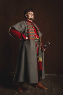 Karanlık bir arka planda Ortaçağ kostümü giymiş bir adamın portresi. Polonyalı güllerin kıyafetleri. Tarihi bir kostümle başlayan gururlu, sıkı adam