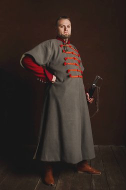 Karanlık bir arka planda Ortaçağ kostümü giymiş bir adamın portresi. Polonyalı güllerin kıyafetleri. Tarihi bir kostümle başlayan gururlu, sıkı adam