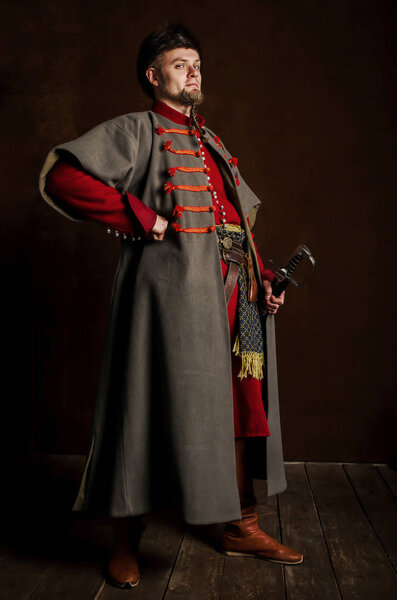 Portrait of a man in a medieval costume on a dark background. Clothes of the Polish gentry. Proud, strict man starting in a historical costume