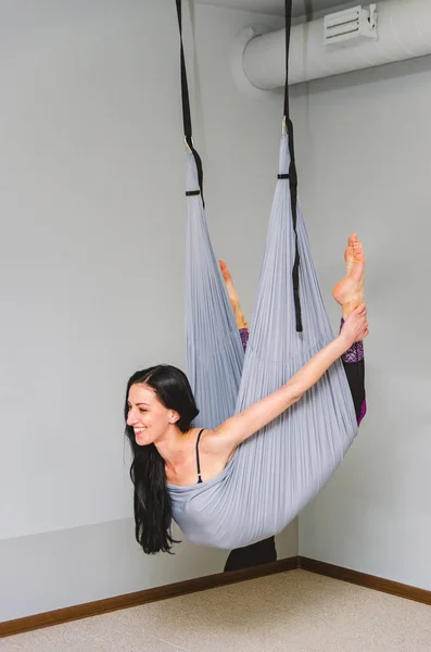 Slim, fit yoga trainer hace volar yoga en una hamaca en el estudio . — Foto de Stock