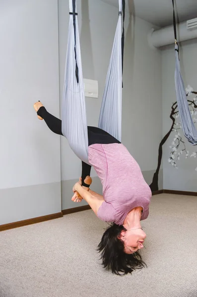 Femme attrayante faisant du yoga de mouche dans un hamac dans le studio — Photo