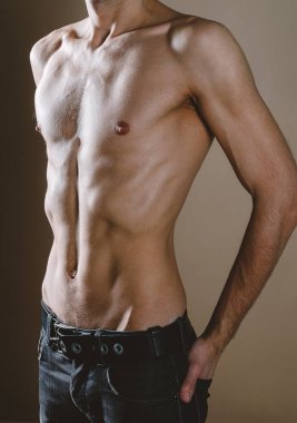 Bej backgroun üzerinde genç, ince, pompalanmış bir adamın çıplak gövde