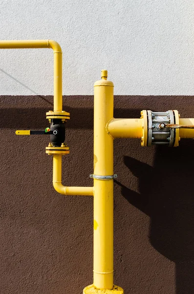 Yellow gas pipe with a crane goes along the facade of a new mult — 스톡 사진