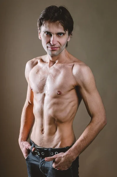 Naked torso of a young, slim, pumped-up man on a beige backgroun — Stock Photo, Image