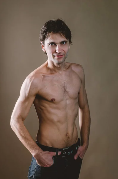 Torso desnudo de un hombre joven, delgado y excitado sobre un fondo beige — Foto de Stock