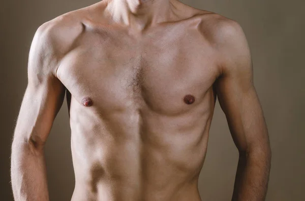 Naked torso av en ung, smal, pumpad upp man på en beige bakgrunds — Stockfoto