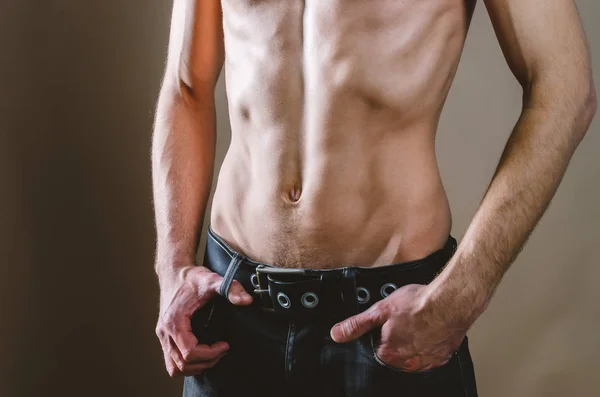Naakte torso van een jonge, slanke, opgepompte man op een beige backgroun — Stockfoto