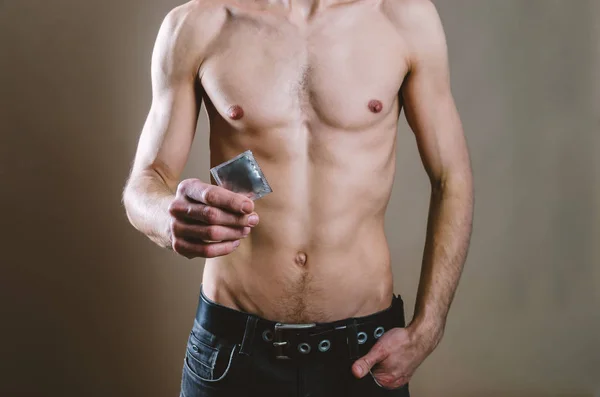 A la cintura un hombre desnudo y atractivo en jeans negros sostiene un cond — Foto de Stock