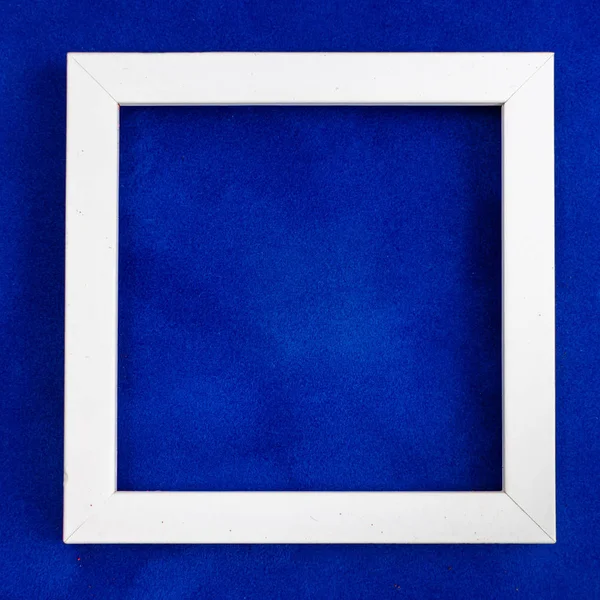 Square white wooden frame on blue velvet background. — Stock Photo, Image