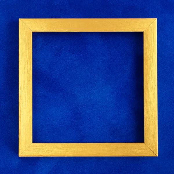 Square golden wooden frame on blue velvet background. — Stock Photo, Image