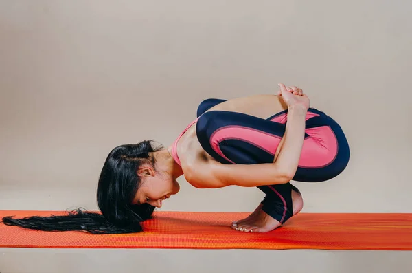 Hermosa mujer en forma slim entrenador se encuentra en asanas sobre una alfombra brillante — Foto de Stock