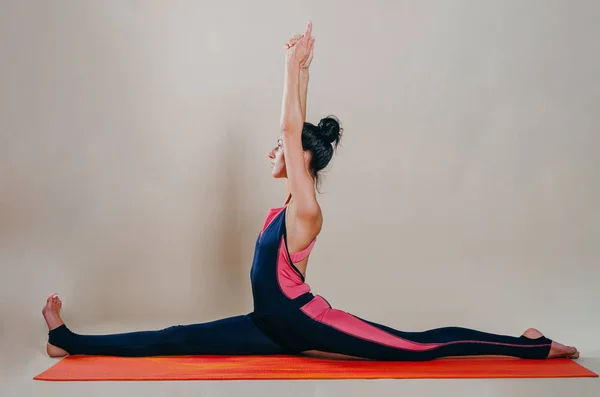 Hermosa mujer en forma slim entrenador se encuentra en asanas sobre una alfombra brillante — Foto de Stock