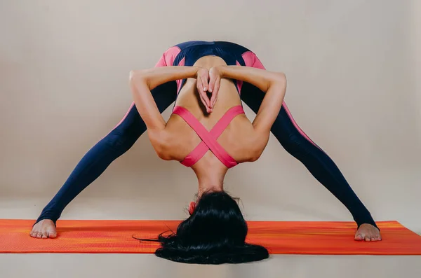 Hermosa mujer en forma slim entrenador se encuentra en asanas sobre una alfombra brillante — Foto de Stock