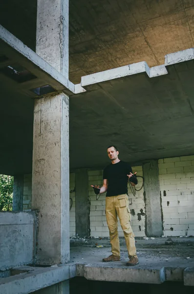 Un homme brutal et séduisant en noir dans un immeuble abandonné. Harceleur — Photo