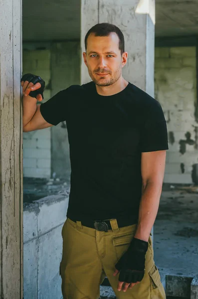 Attractive brutal man in black in an abandoned building. Stalker — Stock Photo, Image