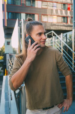 Çekici genç adam (hipster) oturup bir akıllı telefon konuşuyor